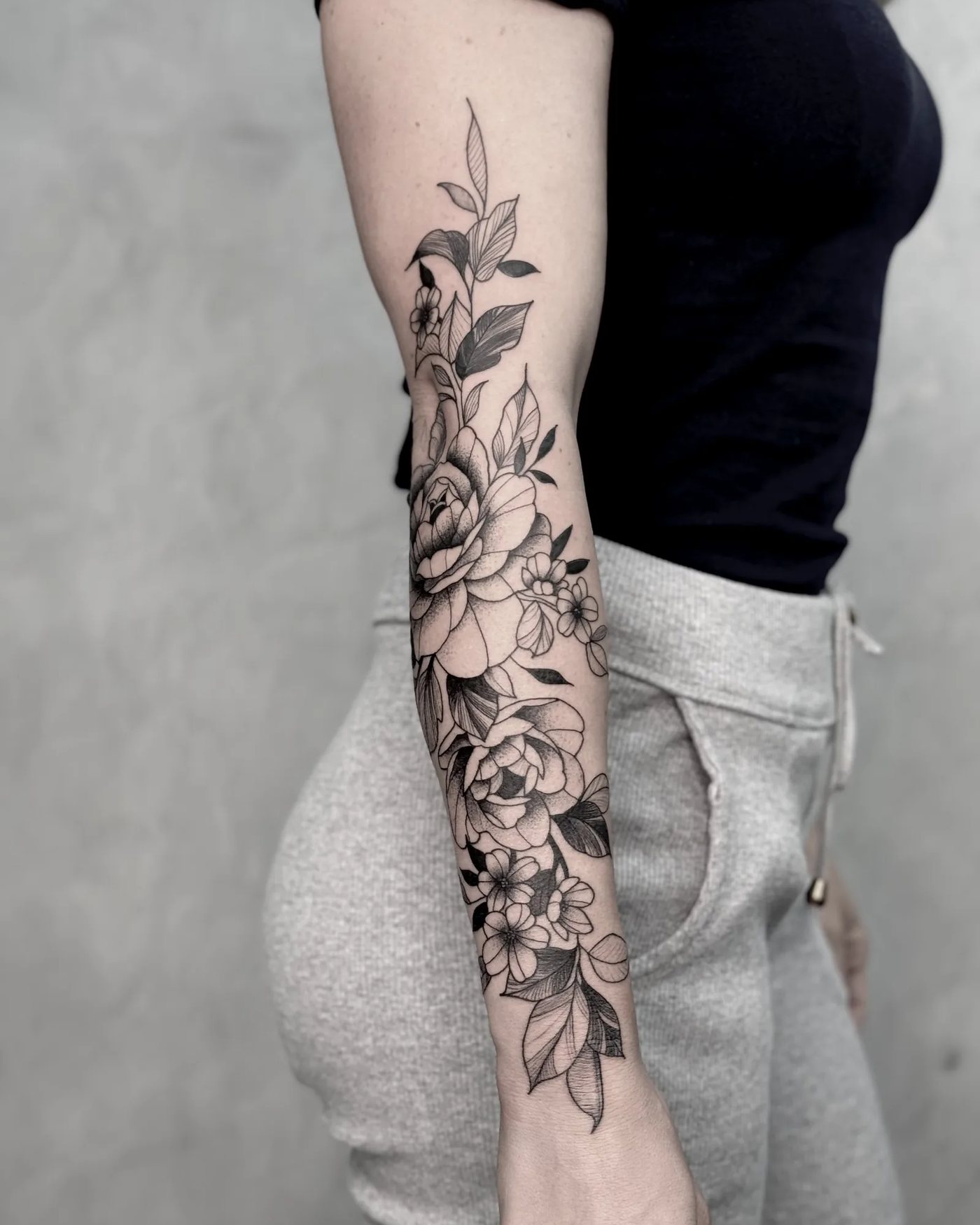 Tatuagem floral em blackwork no antebraço, com rosas e folhas